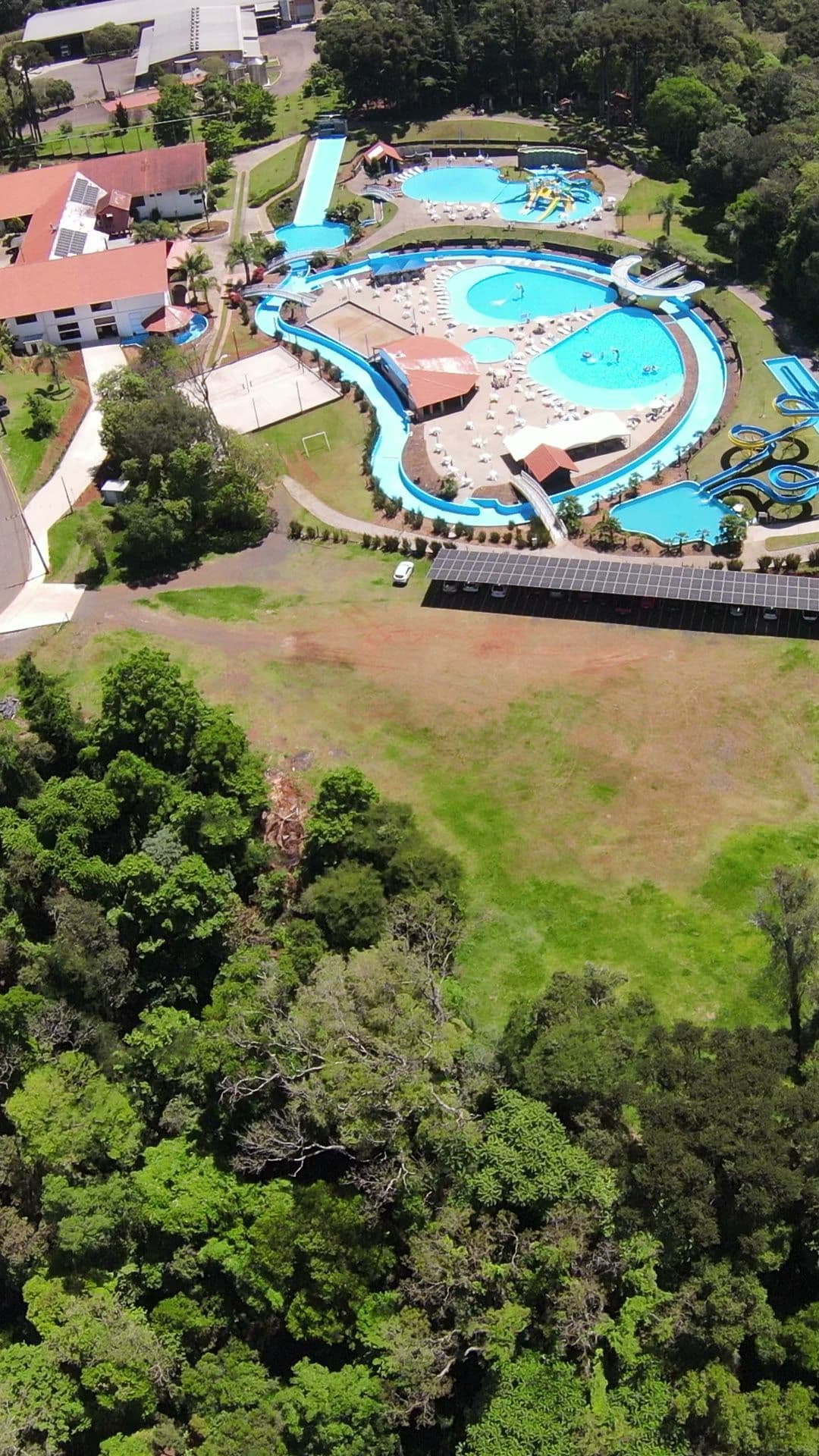 Vista aérea do parque no meio da mata, com as piscinas azuis e os toboáguas.