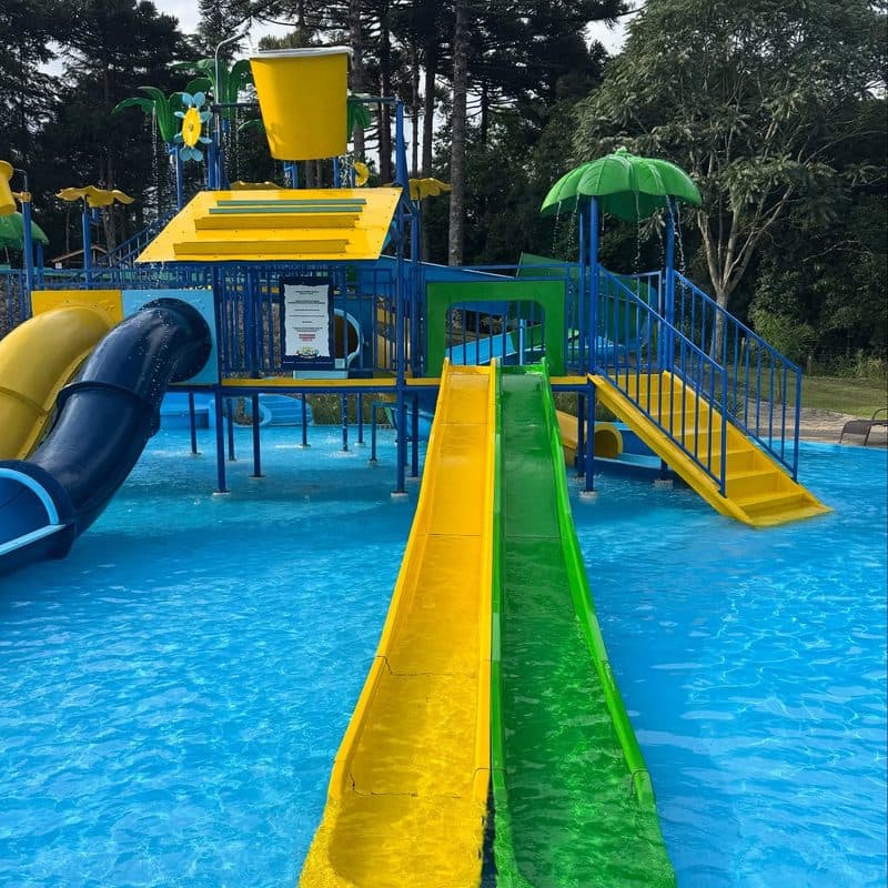 Escorregadores amarelo e verde do brinquedo infantil descendo para a piscina