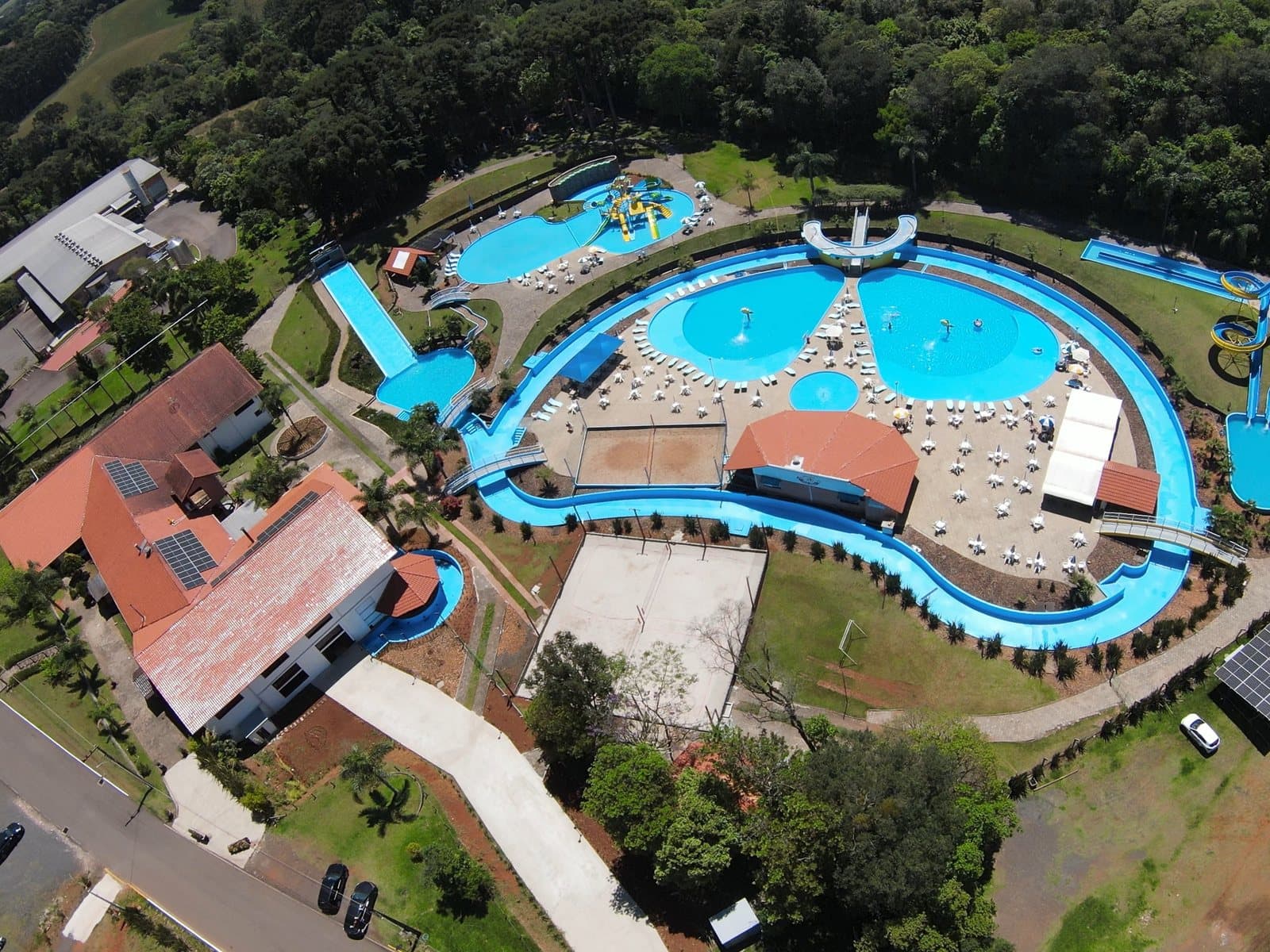Vista aérea do conjunto de piscinas azuis, cercado pelo rio lento e pela mata